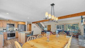 A spacious kitchen with wooden cabinets, a large island, and a dining area with a wooden table and chairs. - AC, foosball, near play ground, hot tub (Sunriver)