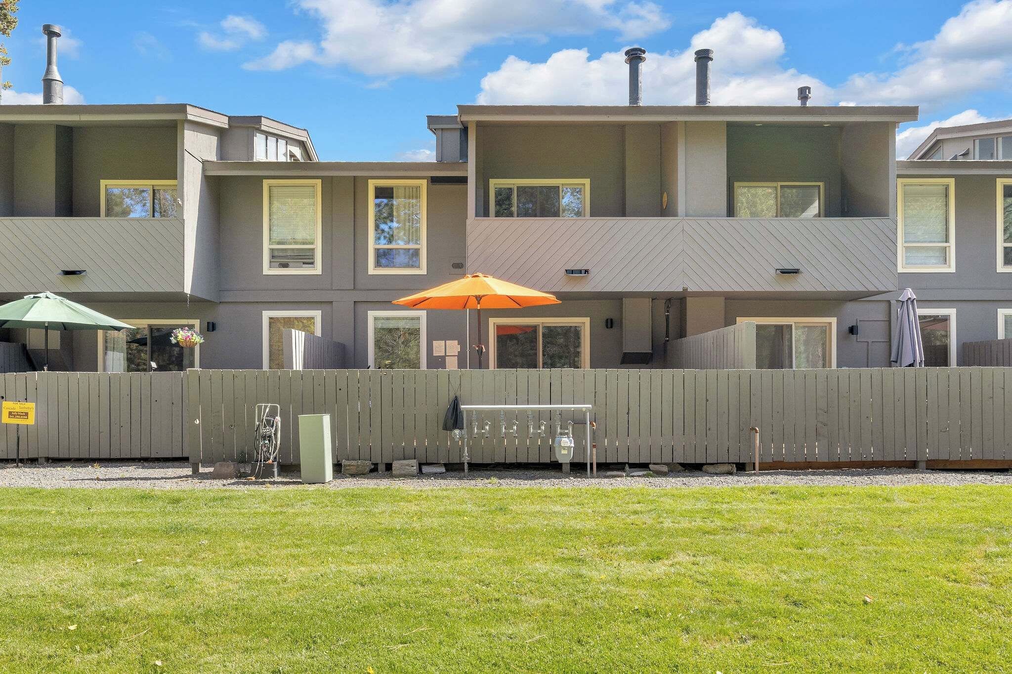 A multi-story residential building with a flat roof, multiple windows, and a fenced yard.
