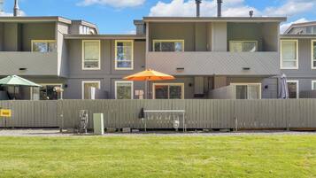 A multi-story residential building with a flat roof, multiple windows, and a fenced yard.
