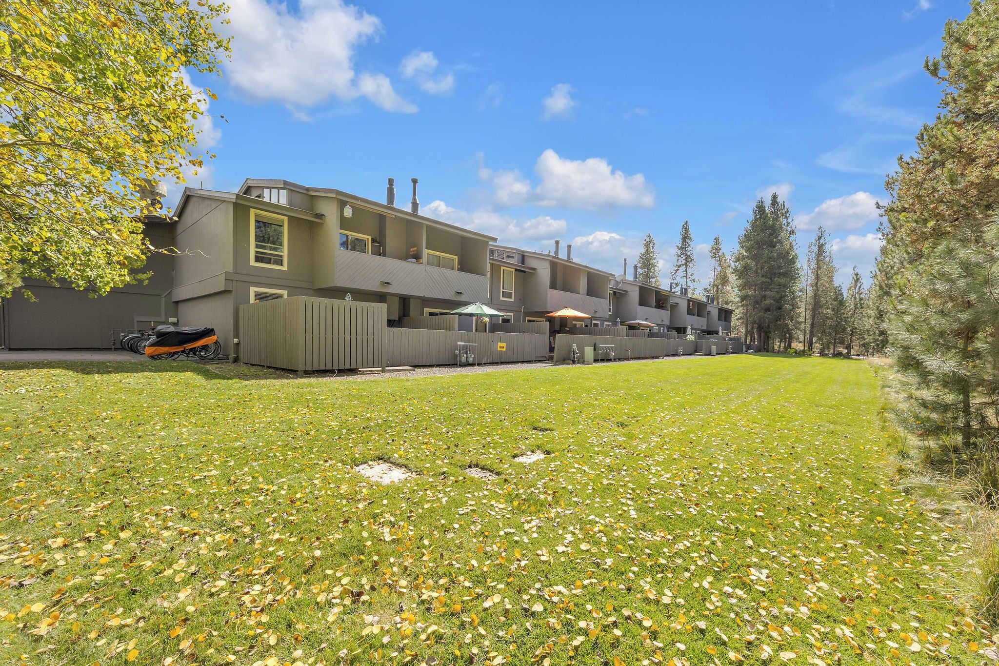 A multi-story building with a flat roof, surrounded by a grassy area with scattered leaves.