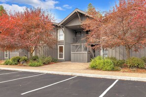 A two-story building with a gray exterior, a front entrance, and a parking lot in front. - Inside Sunriver Village near local shops, eateries (Sunriver)