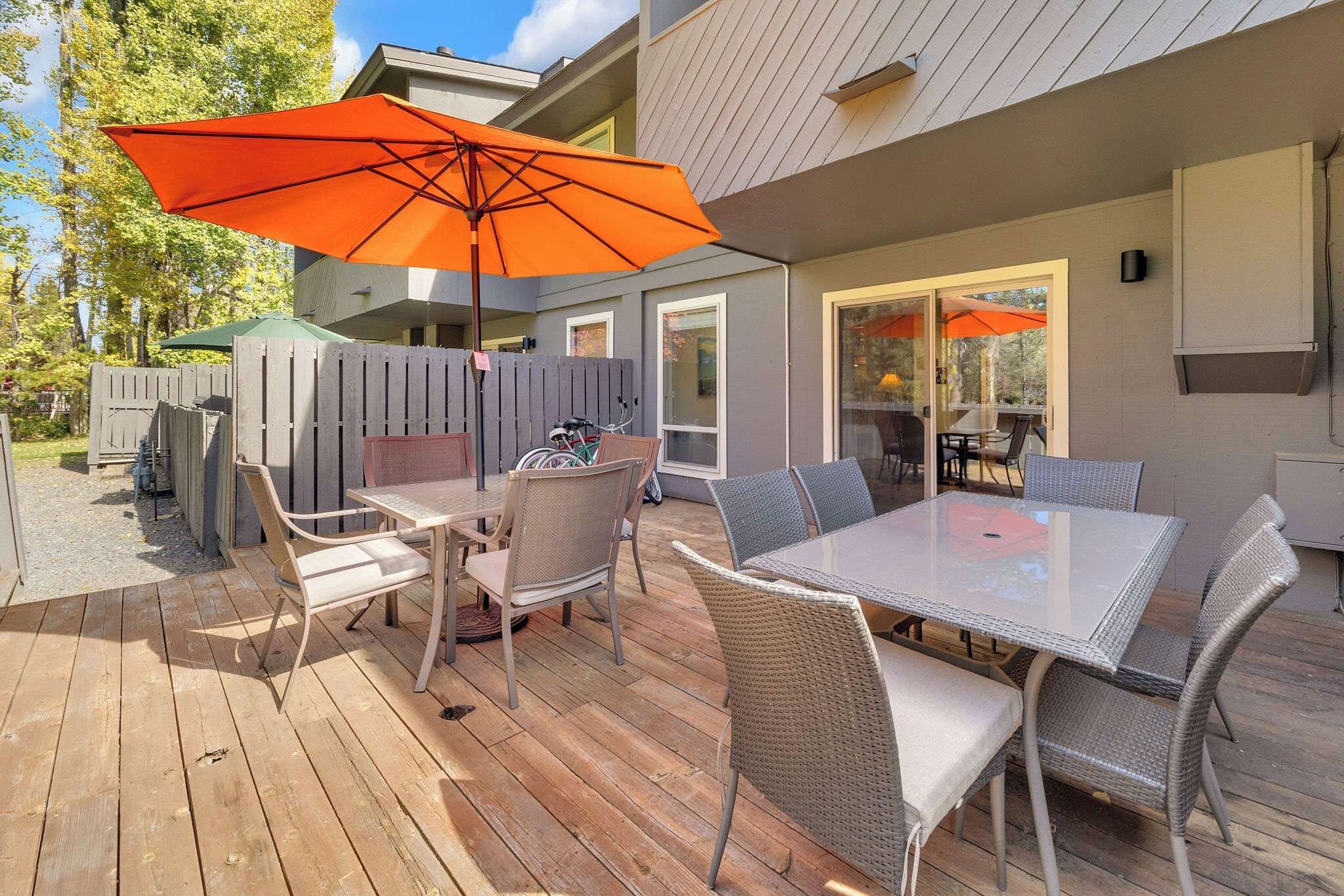 An outdoor patio with a table and chairs, a wooden deck, and a glass door leading to an interior space.