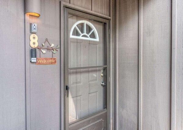 A door with a 'Welcome' sign, a keypad, and a small mailbox.