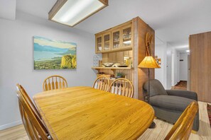 A dining area with a wooden table and chairs, a cabinet with glass doors, and a painting on the wall. - Inside Sunriver Village near local shops, eateries (Sunriver)