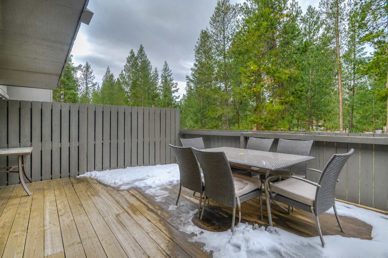 Un patio al aire libre con piso de madera, una mesa y sillas.