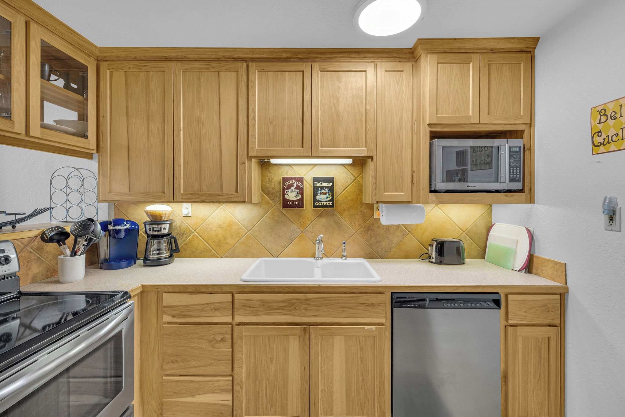 A kitchen with wooden cabinets, a microwave, a coffee maker, and a dishwasher.