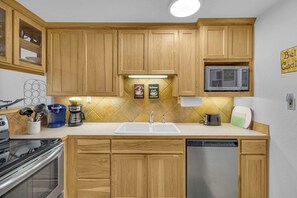 A kitchen with wooden cabinets, a microwave, a coffee maker, and a dishwasher. - Inside Sunriver Village near local shops, eateries (Sunriver)