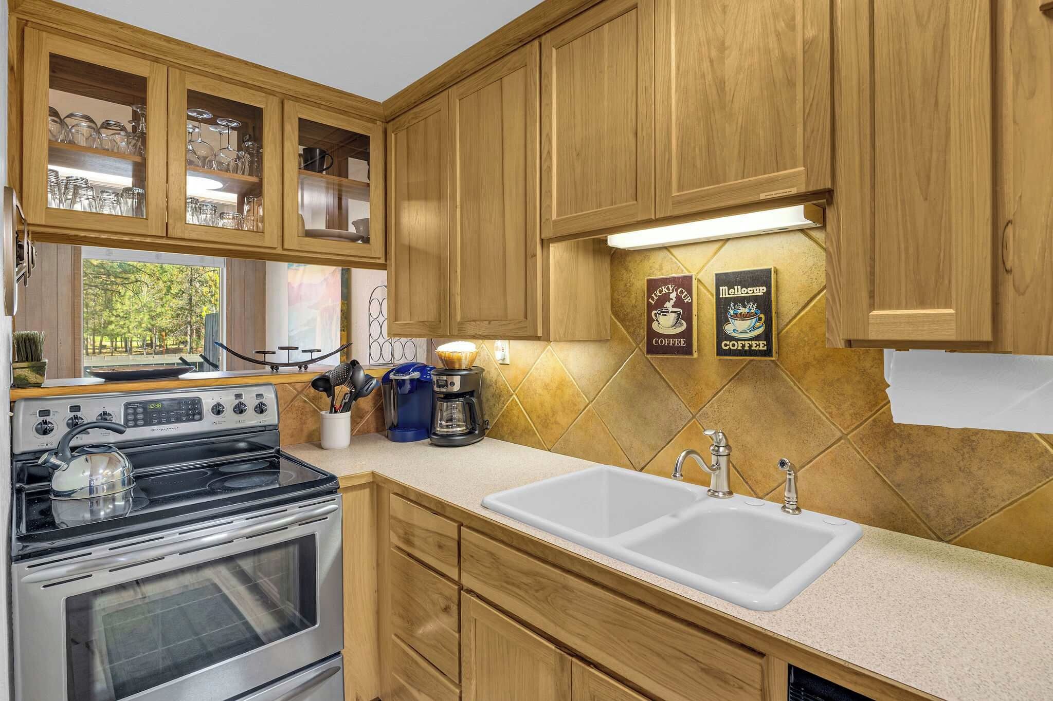 A kitchen with wooden cabinets, a stove, a coffee maker, and a sink.