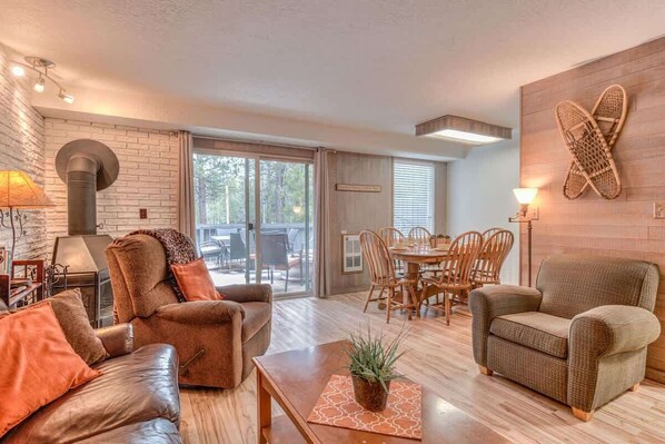 A spacious living room with a fireplace, leather sofas, a dining area, and a large window.