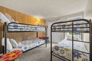 A room with two bunk beds, wooden paneling on the walls, a window, and a lamp. - Inside Sunriver Village near local shops, eateries (Sunriver)