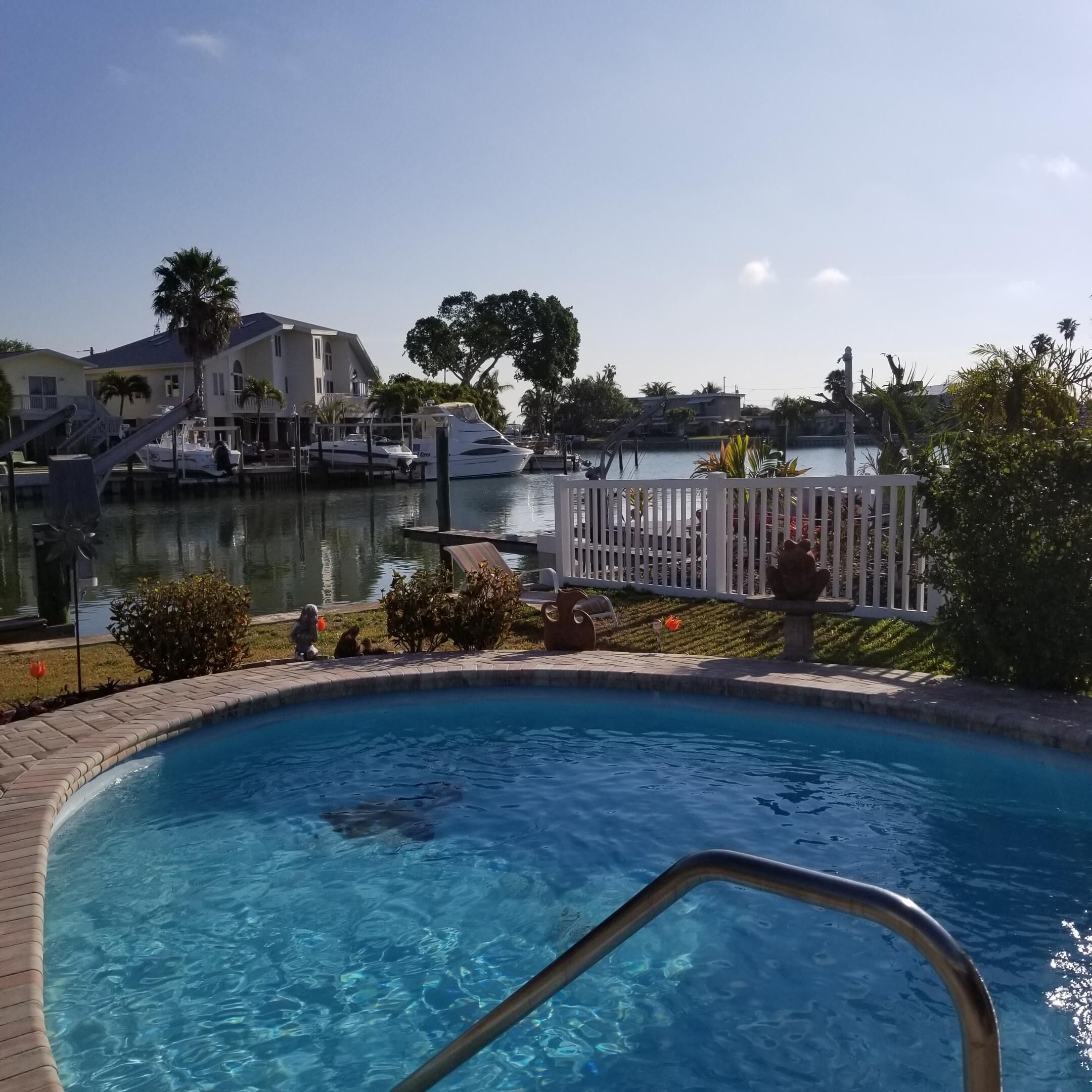 A swimming pool with a clear view of a marina and houses in the background.