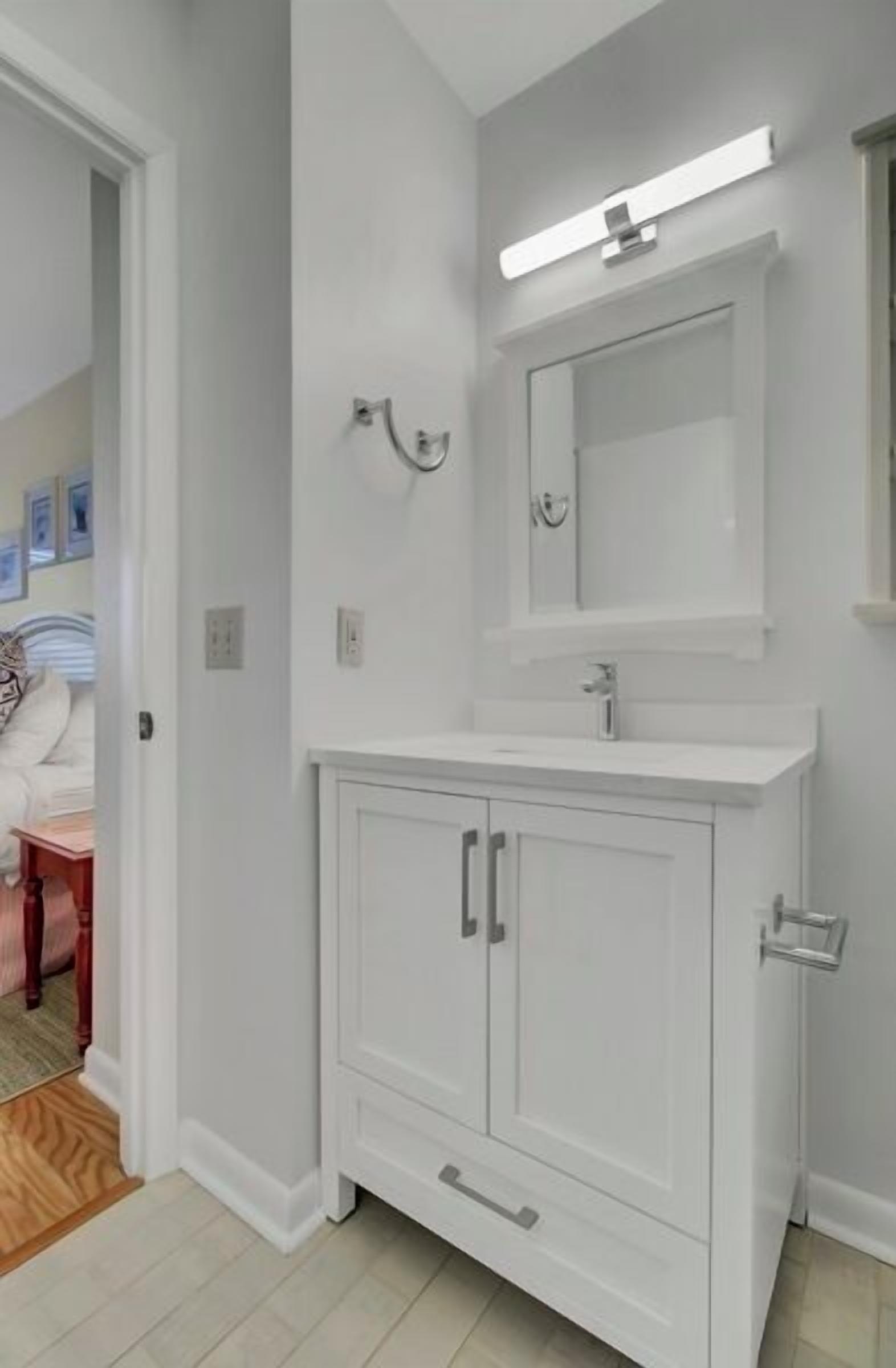 Une salle de bain avec un meuble-lavabo blanc, un miroir et un luminaire.
