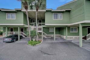 A two-story building with a green exterior, a covered outdoor area, and a car parked in front. - Award-Winning Resort Amenities | Mariners Walk 7F (Isle of Palms)