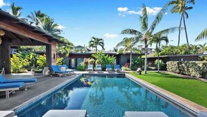 A swimming pool with lounge chairs, palm trees, and a well-maintained lawn. - Plantation House (Kihei)