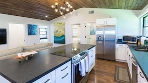 A modern kitchen with a large island, stainless steel appliances, and a wooden ceiling. - Plantation House (Kihei)