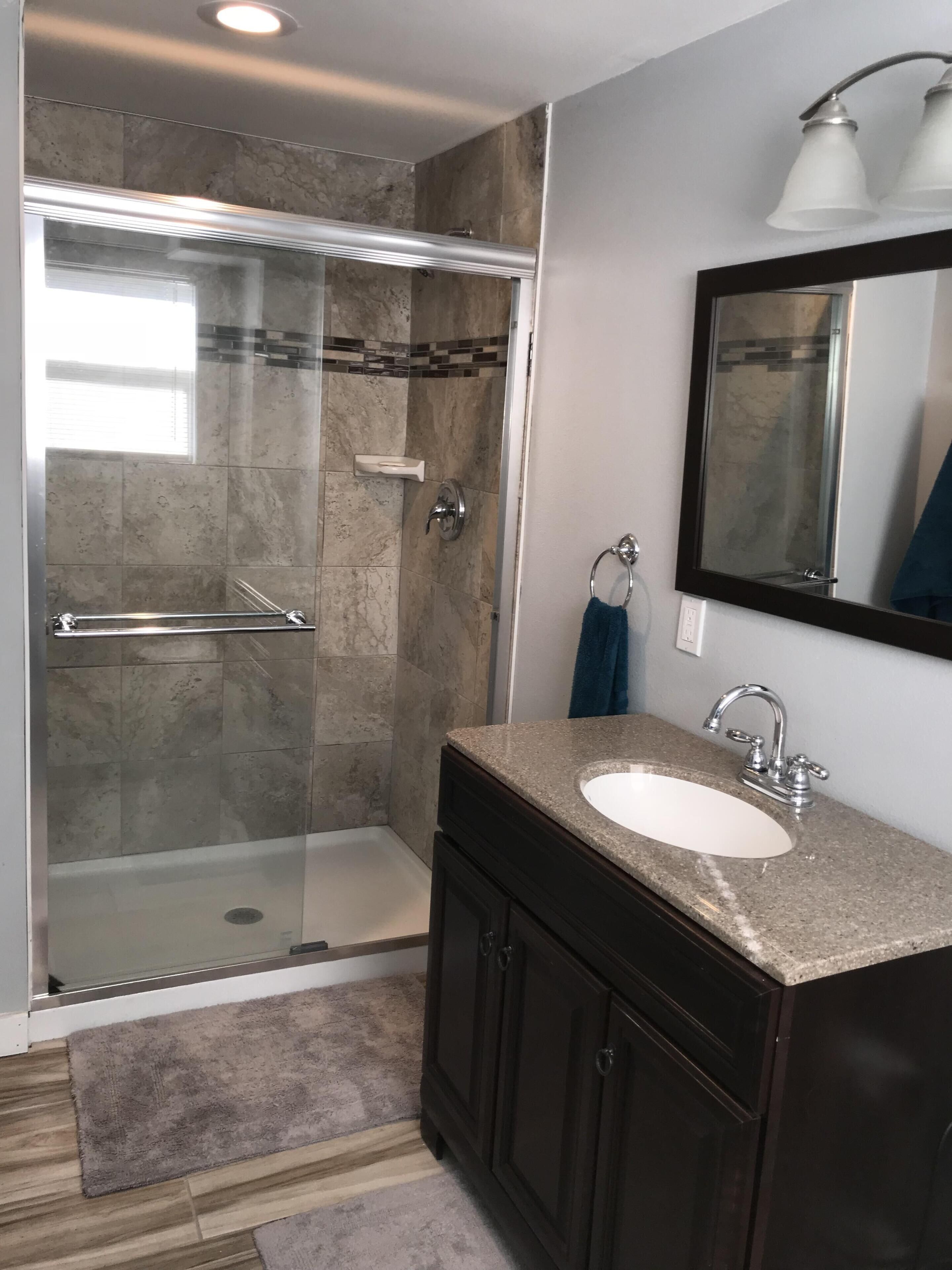 Une salle de bain moderne avec une douche à parois de verre, un meuble-lavabo et un miroir au-dessus du lavabo.