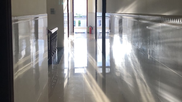 A hallway with reflective tiled floors and walls, leading to a doorway. - Hong Ngoc Hotel (Ho Chi Minh City)