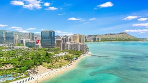 Une vue urbaine d’une ville côtière, avec un hôtel imposant qui se distingue par une grande icône rouge en forme d’épingle, indiquant son emplacement.