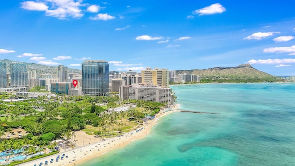 A coastal cityscape with a beachfront, high-rise buildings, and a mountain in the background.