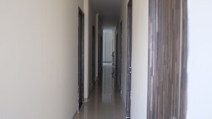Un pasillo largo y estrecho con puertas a ambos lados, que conduce a una habitación al final.
