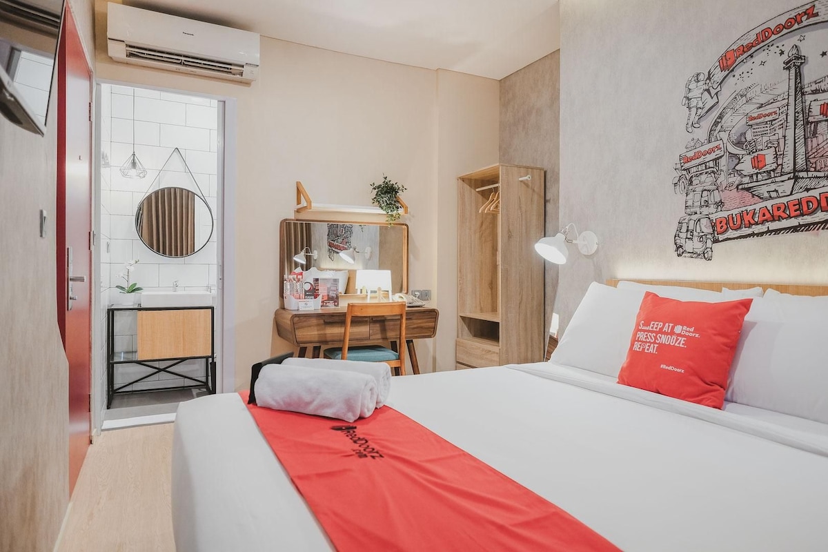 A hotel room with a bed, a desk, a wardrobe, and a bathroom.
