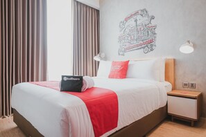 A hotel room with a bed, a nightstand, a lamp, a wall art, and a window with curtains. - RedDoorz Plus @ Thamrin (Jakarta)