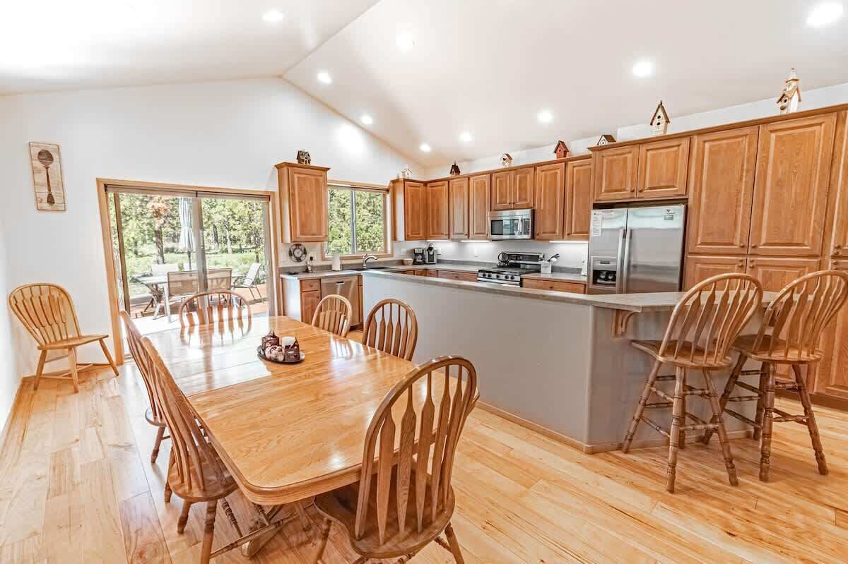 A spacious kitchen with wooden cabinets, a large island, and a dining area with wooden chairs.