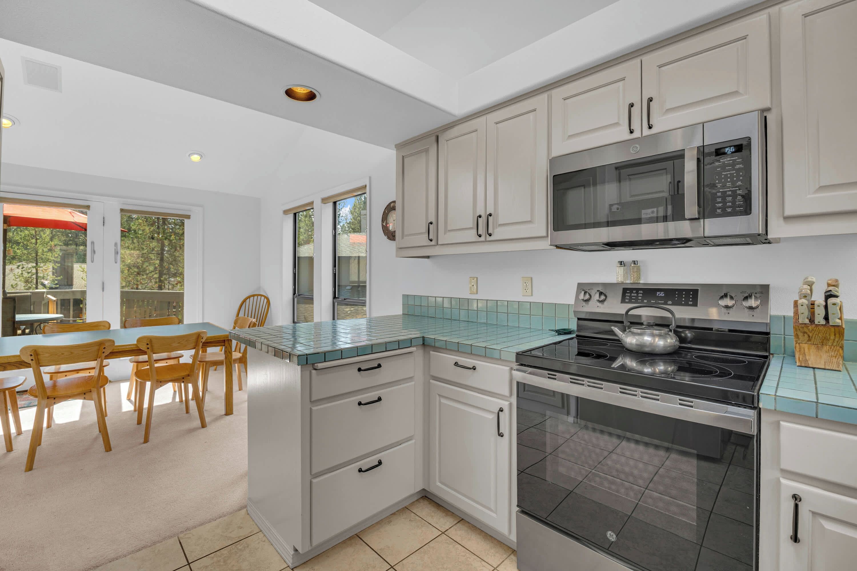 A modern kitchen with white cabinets, a stainless steel stove, and a microwave.