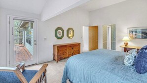 Une chambre avec un grand lit, une commode en bois et une porte donnant sur un balcon.