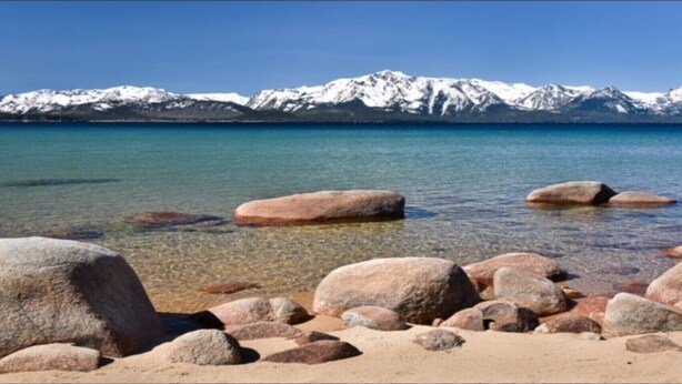 A beach with clear water and large rocks in the foreground, and snow-capped mountains in the background. - Make Memories in Marla Bay, Private Homeowners Beach, 8 Guests (Zephyr Cove)
