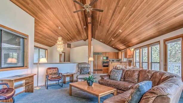A spacious living area with a wooden ceiling, a large brown leather sofa, a coffee table, and a dining table. - Panoramic mountain views hot tub, air conditioning (Sunriver)