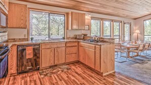 A modern kitchen with wooden cabinetry, a built-in island, and large windows. - Panoramic mountain views hot tub, air conditioning (Sunriver)