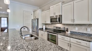 A modern kitchen with granite countertops, stainless steel appliances, and white cabinetry.