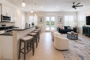 Una cocina moderna con barra, comedor y sala de estar con sofá y mesa de centro.