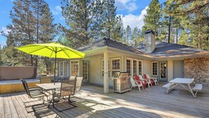 A wooden deck with outdoor furniture, including a table and chairs, and a bright yellow umbrella. - Single level Sunriver rental, large deck, hot tub (Sunriver)