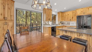 Una cocina moderna con armarios de madera, un refrigerador de acero inoxidable y una zona de comedor con mesa y sillas de madera.