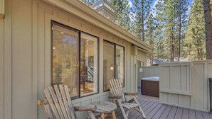 Una terraza de madera con sillas Adirondack y un jacuzzi.