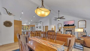 A spacious living room with a large wooden dining table, a fireplace, and a television. - Hot Tub, AC, Ping Pong, Foosball, 4bdrm, Family (Bend)