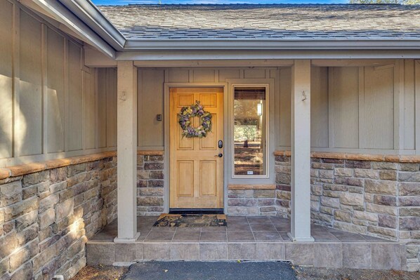 A house with a stone exterior, a wooden front door, and a wreath on the door.