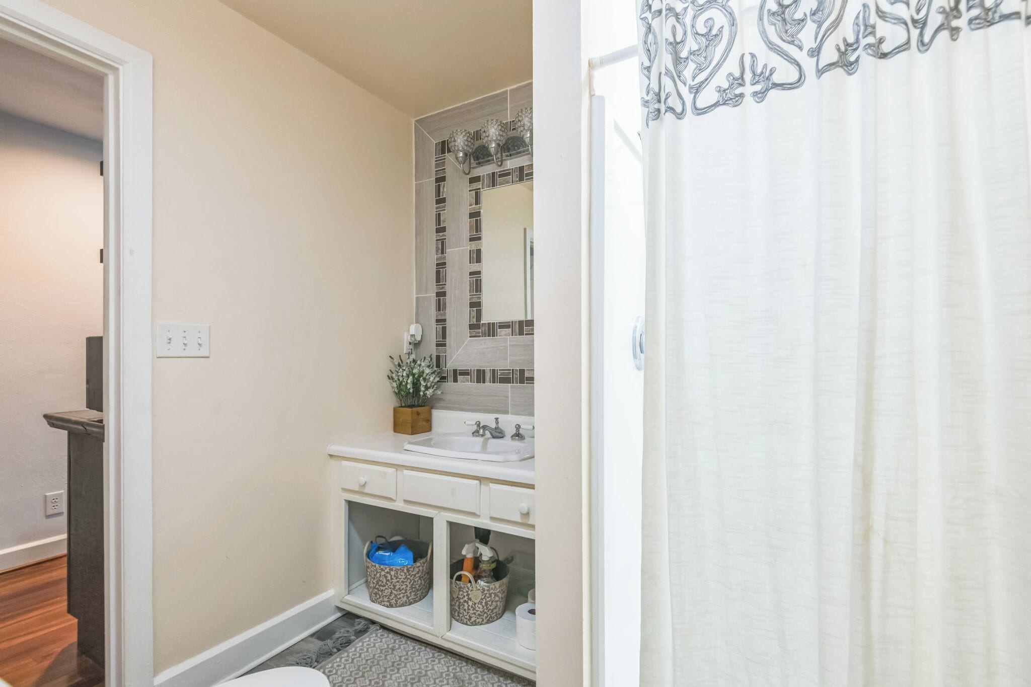 A bathroom with a white sink, mirror, and storage baskets.