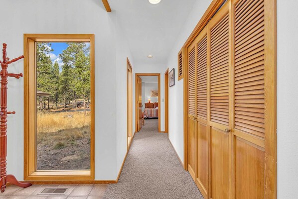 A hallway with a large window, wooden shutters, and a carpeted floor. - Unique, spacious, private deck, HT, great room (Sunriver)
