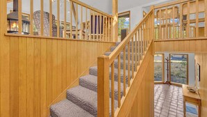 A wooden staircase with a view of a fireplace and outdoor scenery. - Unique, spacious, private deck, HT, great room (Sunriver)