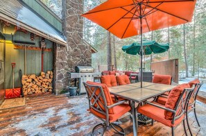 Eine Terrassengruppe mit Steinsichtwand, Grill und Sonnenschirmen in Orange und Grün.
