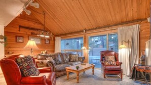 Ein gemütliches Blockhaus-Interieur mit einem Ledersofa, einem roten Sessel, einem Holztisch und einem Kamin.