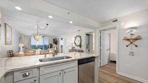 Una cocina moderna con una isla grande, armarios blancos y vistas al exterior.