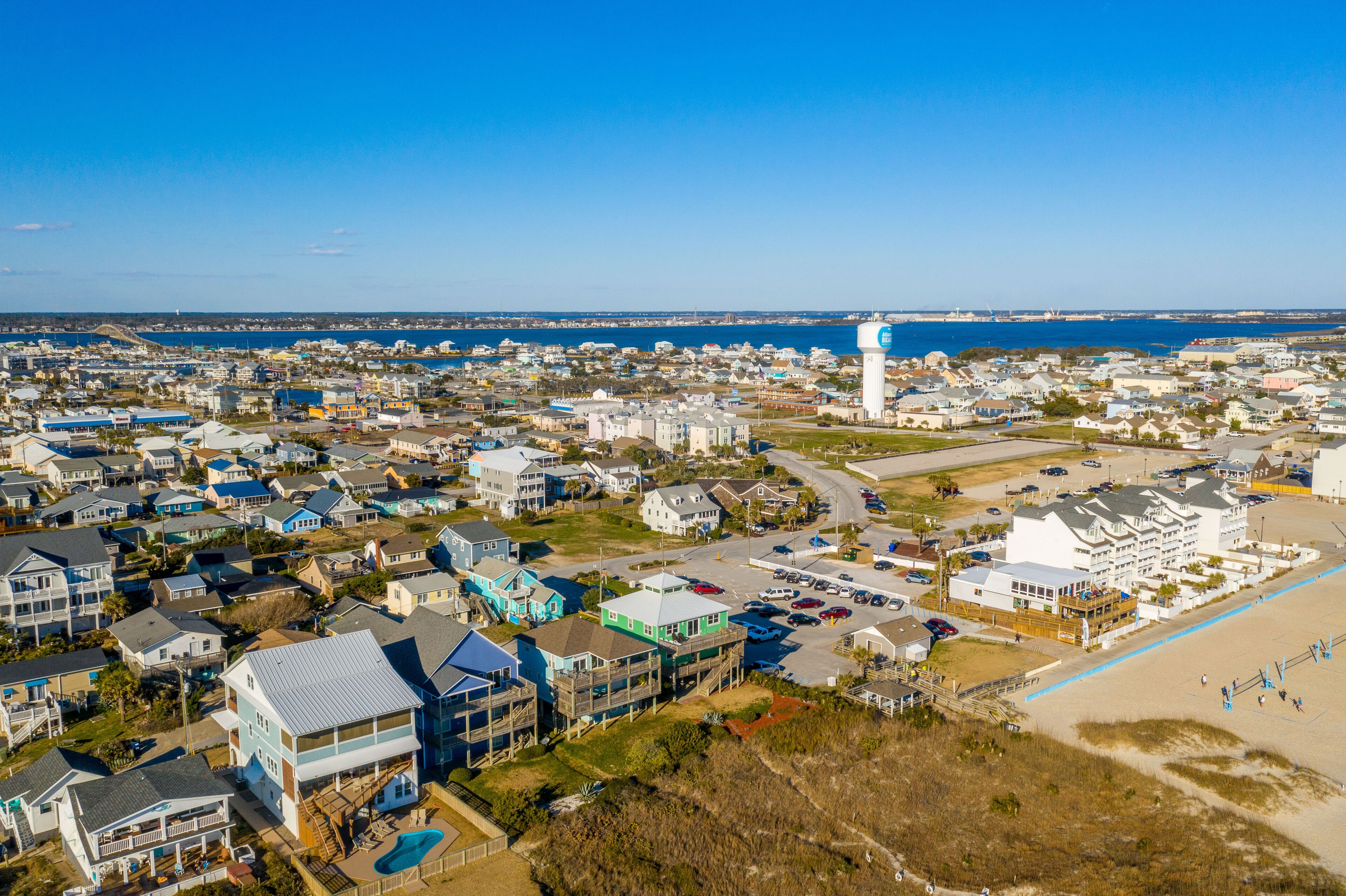 A coastal residential area with houses, a beach, and a large white building with a blue roof.