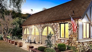 A stone building with arched windows, a flag, and outdoor seating.
