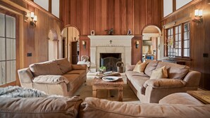 A spacious living room with high wooden ceilings, a fireplace, and a cozy seating area with sofas and a coffee table.