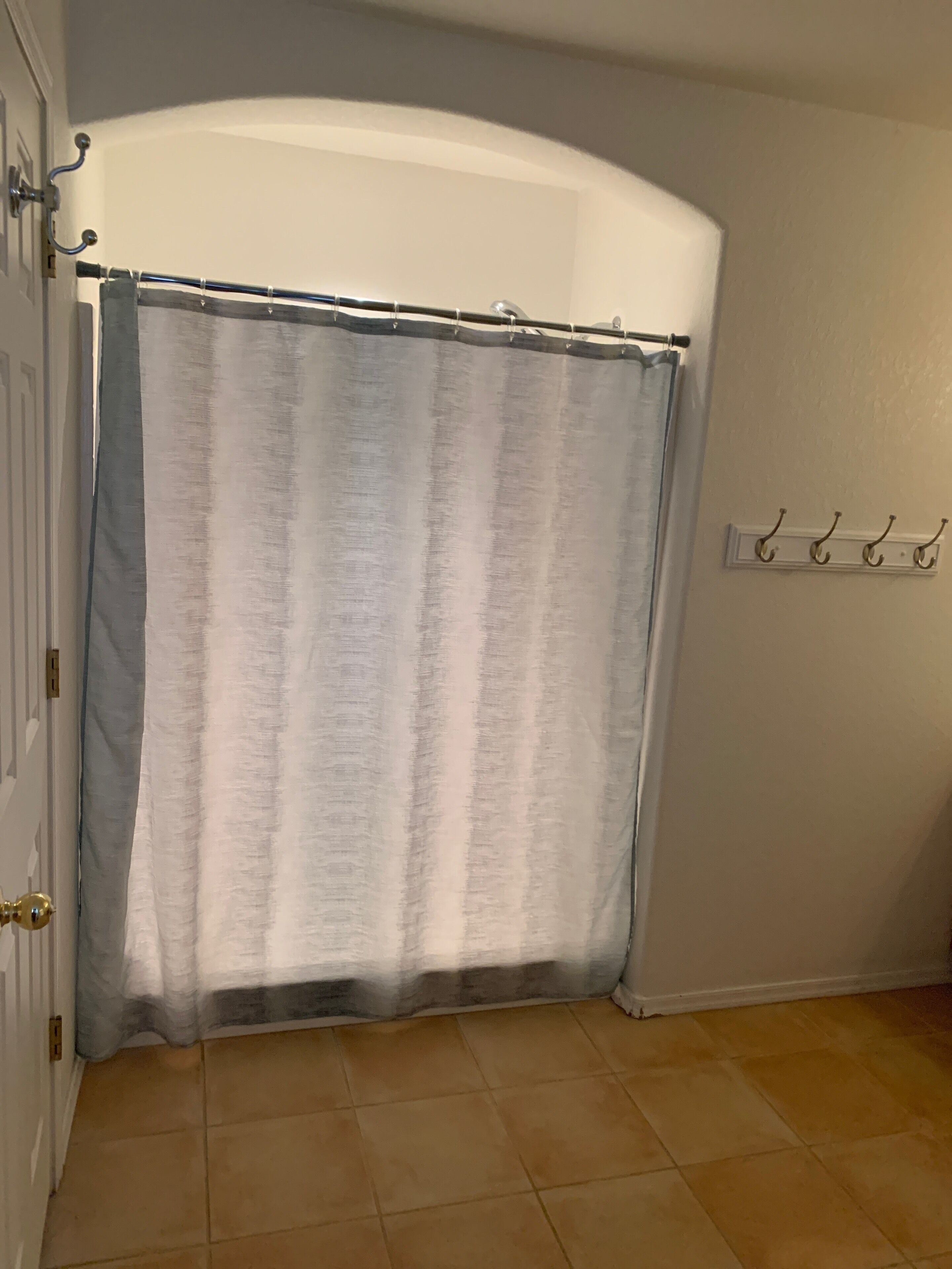 A bathroom with a shower curtain, a towel rack, and a tiled floor.