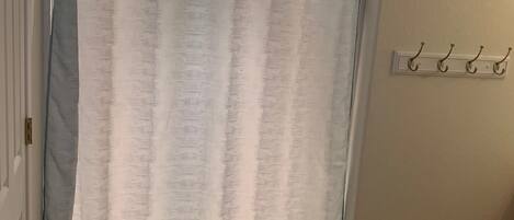 A bathroom with a shower curtain, a towel rack, and a tiled floor.